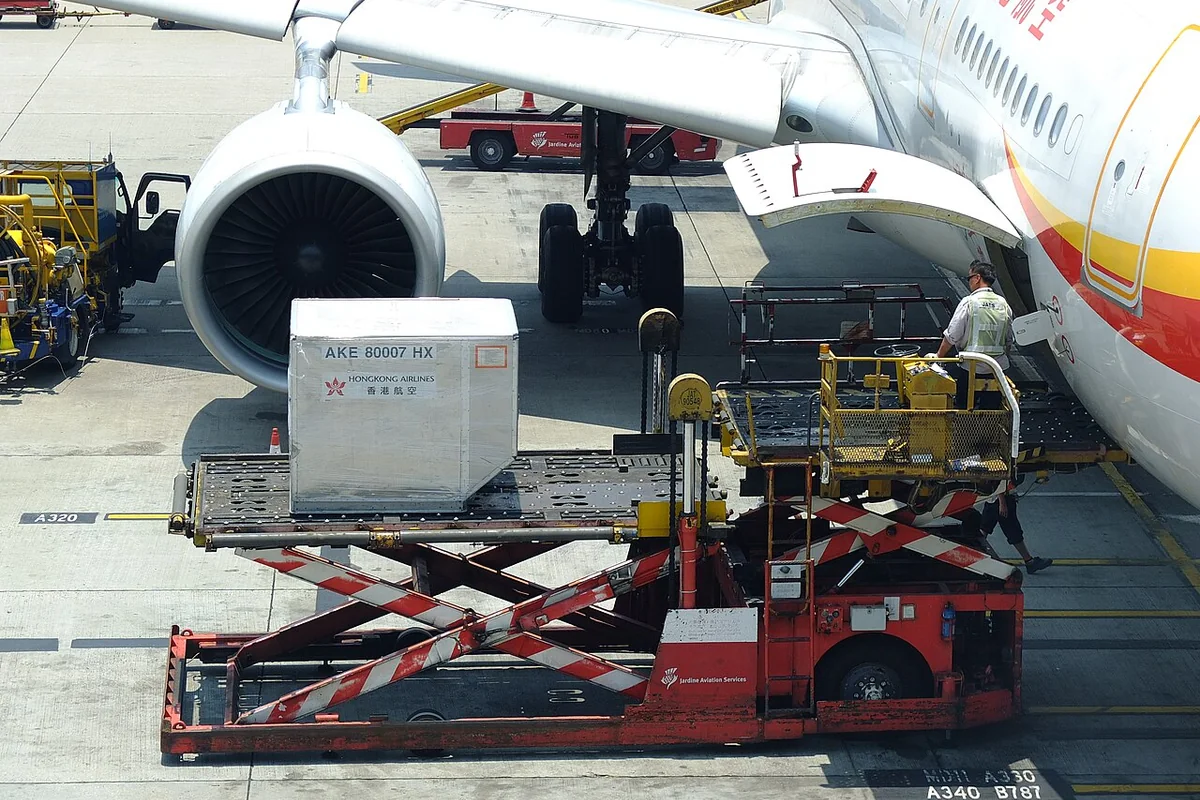 Unit Load Device (ULD) cargo container loader operating at the airport apron during priority flight staging.