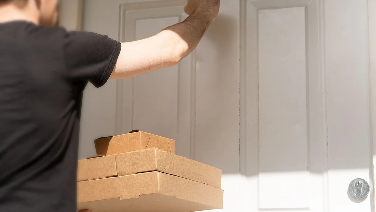 Courier knocking on a residential front door attempting parcel delivery.