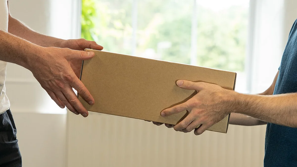 Hands completing a parcel handover during weekend courier operations.