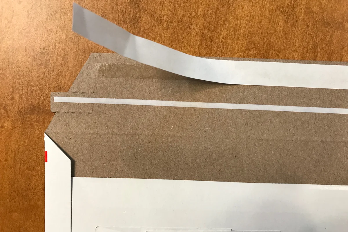 Rigid paperboard document mailer envelope featuring adhesive peel strip for tamper-resistant sealing